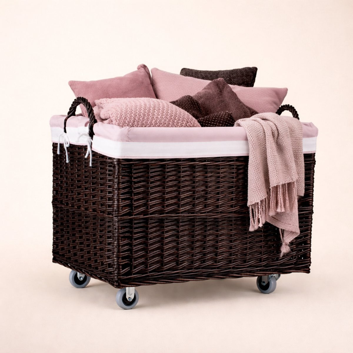 The Wicker Stories Grote donkere rieten mand op wielen met handgrepen en roze stoffen voering