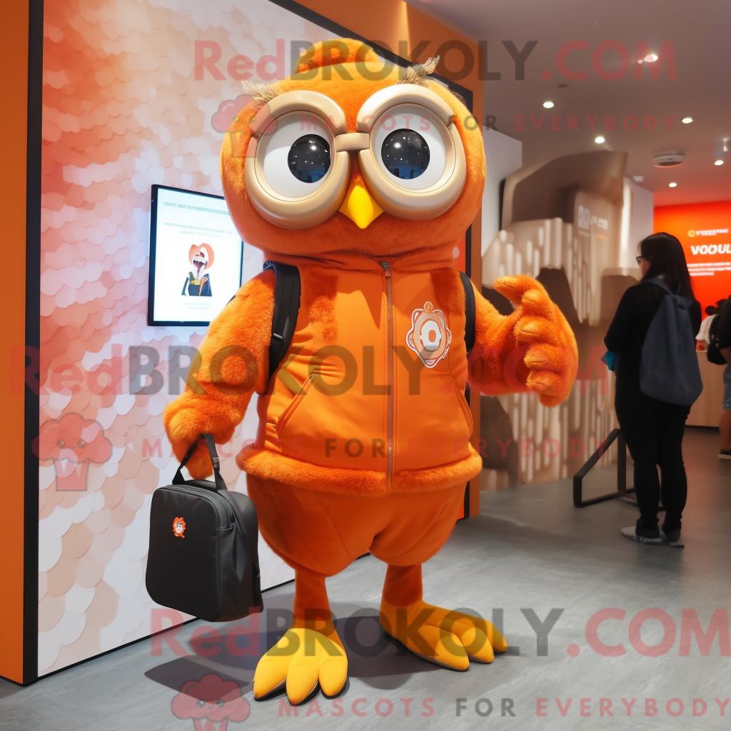 Maskottchen REDBROKOLY einer orangefarbenen Eule mit Spielanzug und Messenger-Tasche