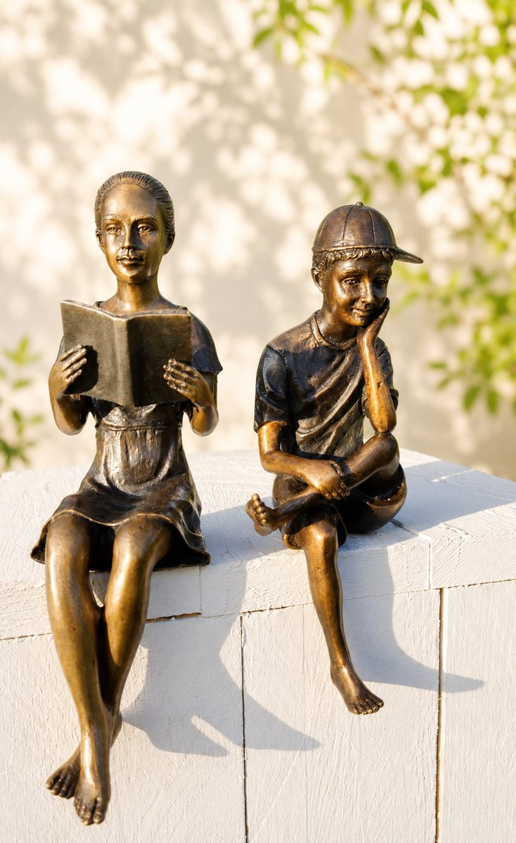 Set van twee bronzen beelden: jongen met pet en lezend meisje
