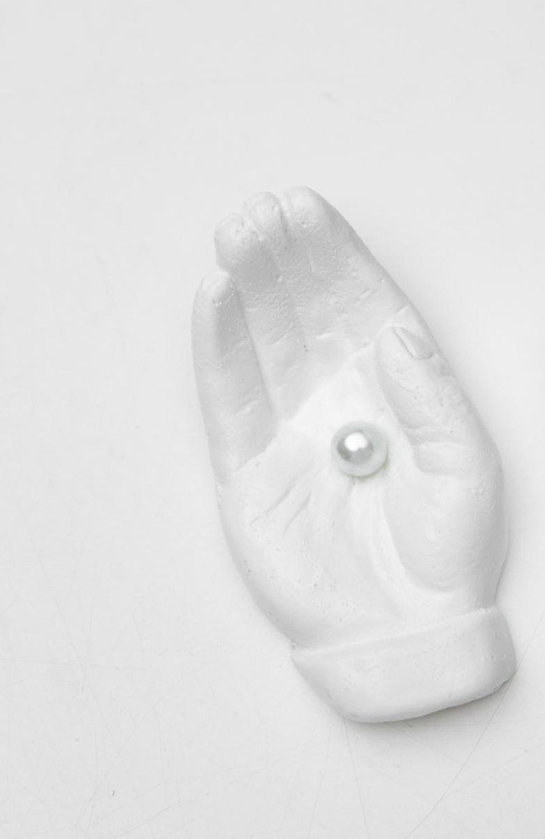 Beeld van een hand met parel in wit
