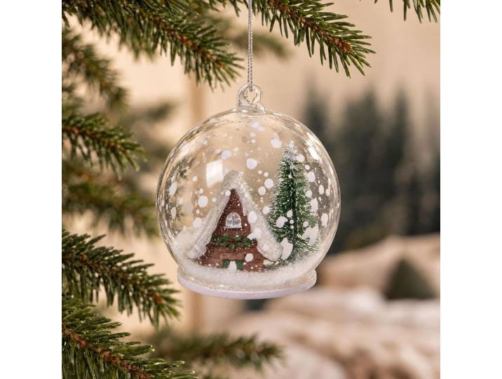 Weihnachtskugel aus durchsichtigem Glas und schneebedecktes Chalet