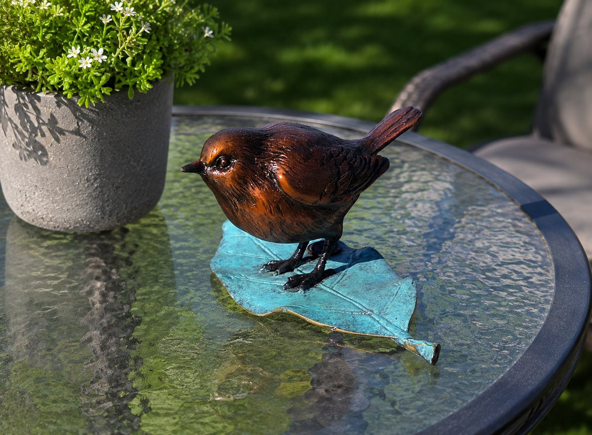 Bronskleurig beeld van een winterkoninkje op een blad