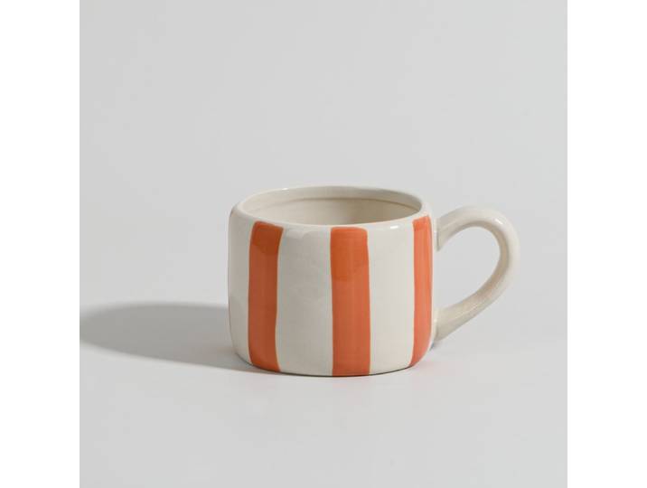 Weißer und orangefarbener Keramikbecher